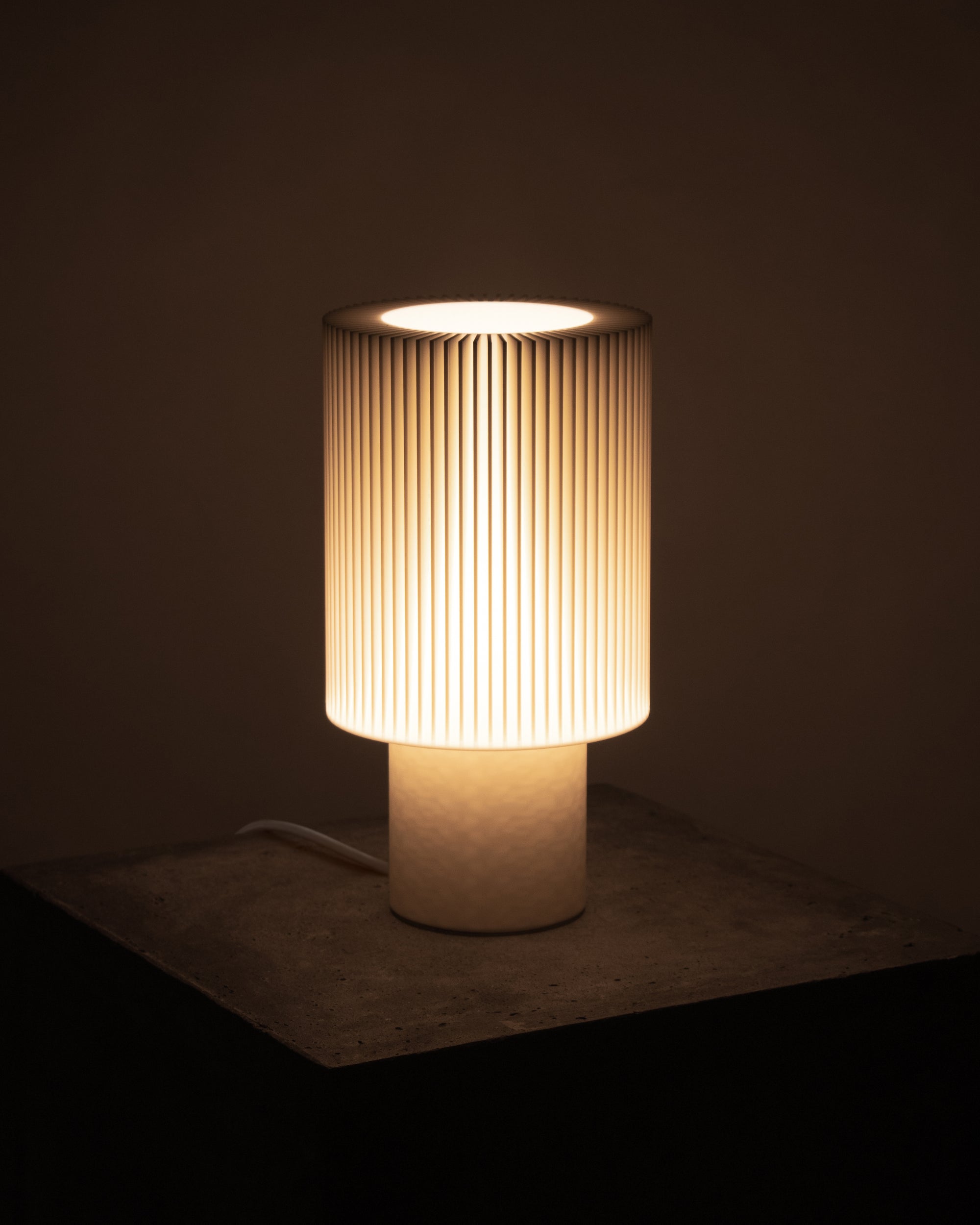 Lampe Iris Colors – Ivoire allumée, diffusant une lumière douce et apaisante à travers un abat-jour nervuré, ambiance feutrée et naturelle.