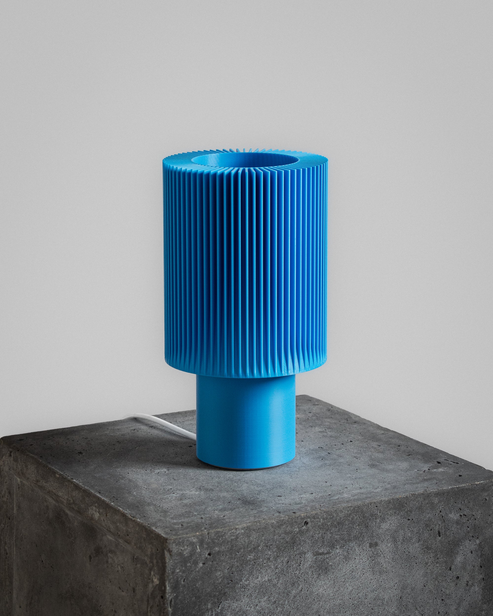 Lampe Iris Colors – Azur éteinte, imprimée en 3D, posée sur un socle en béton brut, bleu vif éclatant et design nervuré graphique.